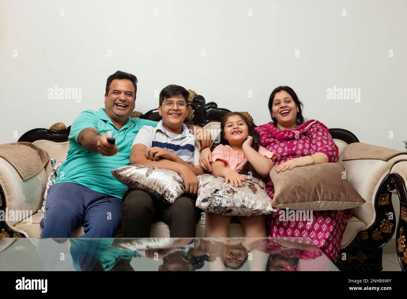 Family watching TV together while sitting on sofa in living room Stock Photo