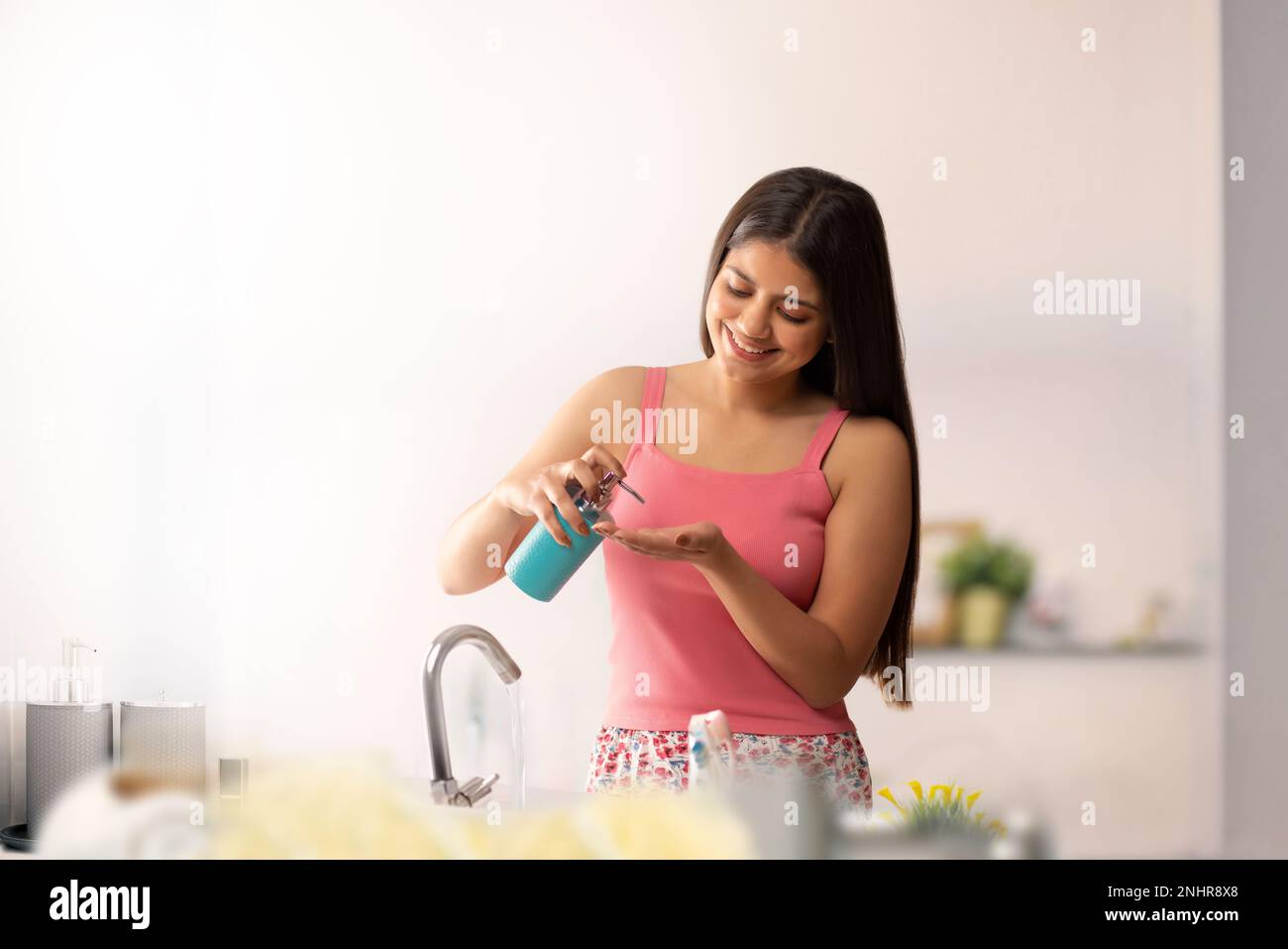 Woman cleaning her hands with liquid hand wash in bathroom Stock Photo