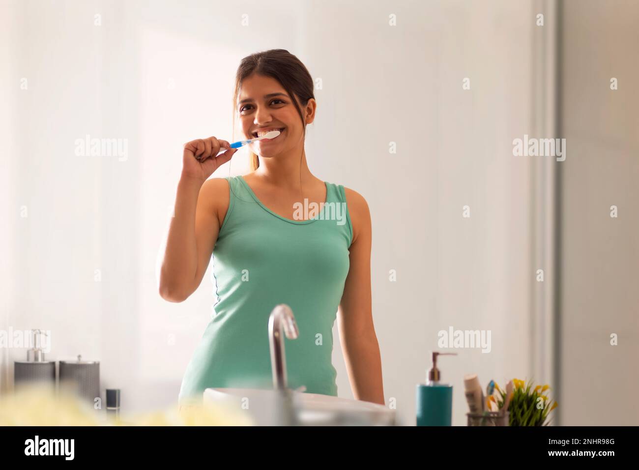 Young woman brushing her teeth in bathroom Stock Photo