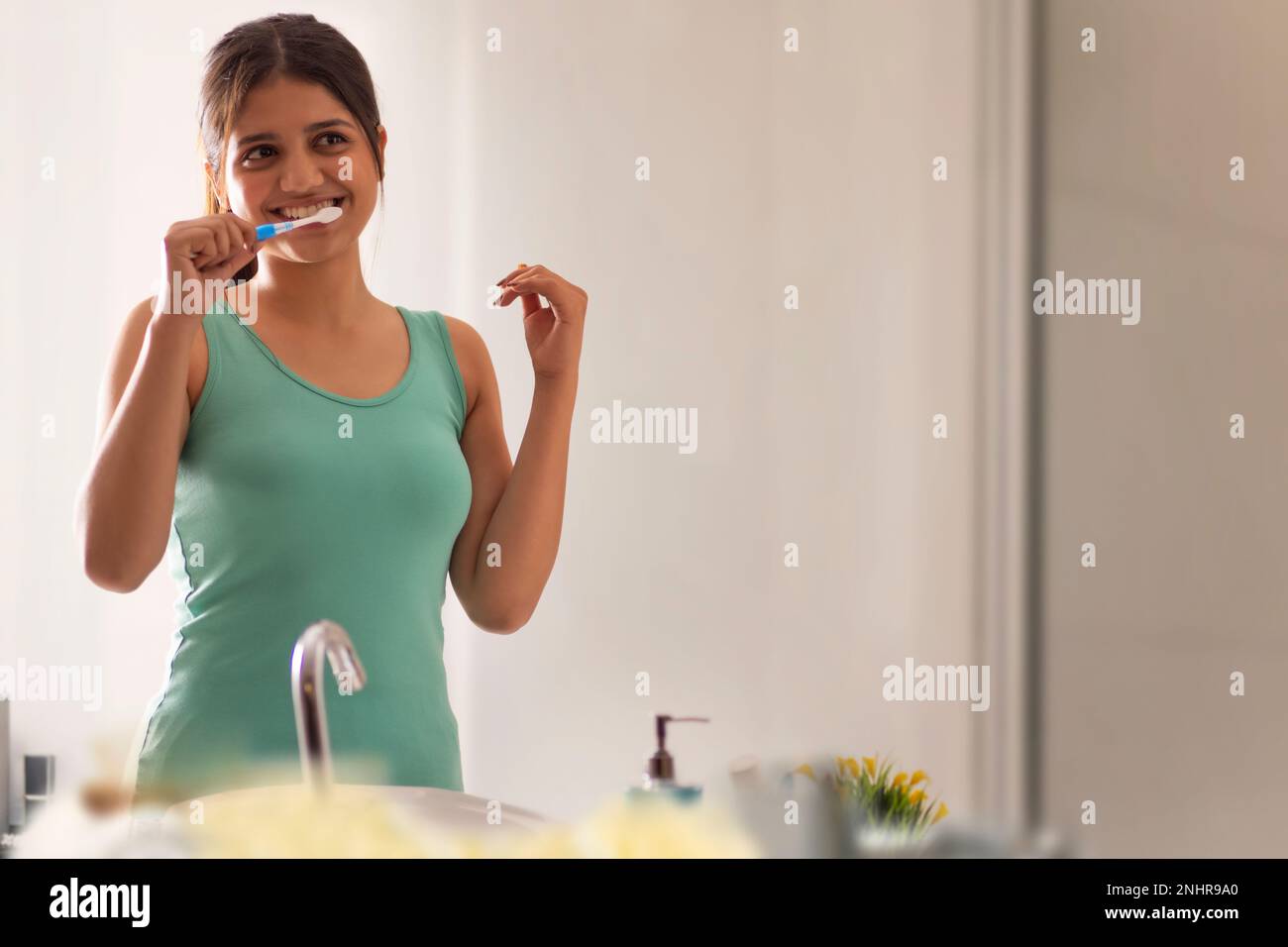 Young woman brushing her teeth in bathroom Stock Photo