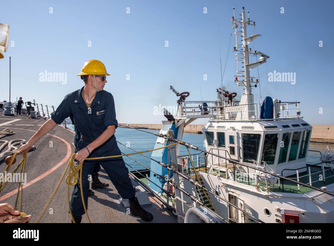 220802-N-QI593-1094 CIVITAVECCHIA, Italy (Aug. 2, 2022) Boatswain's Mate 2nd Class Michael Marcalus, from Berkeley Springs, West Virginia, throws a heaving line to a tugboat from the fo’c’sle aboard the Arleigh Burke-class guided-missile destroyer USS Bainbridge (DDG 96) during a scheduled port visit to Civitavecchia, Italy,  Aug. 2, 2022. Bainbridge is on a scheduled deployment in the U.S. Naval Forces Europe area of operations, employed by U.S. Sixth Fleet to defend U.S., allied and partner interests. Stock Photo