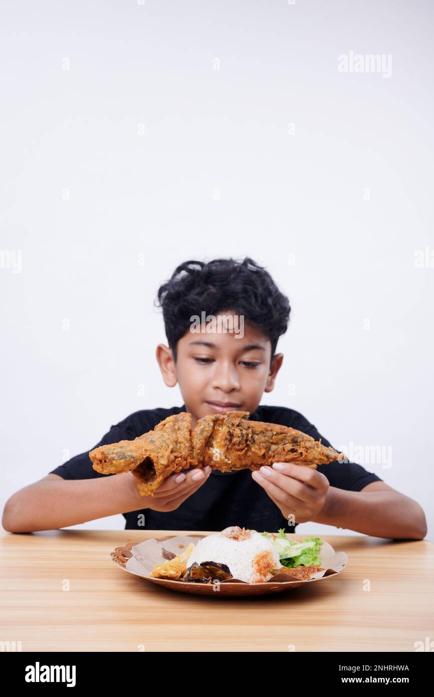 Asian boy enjoys fried fish and rice at lunch time Stock Photo - Alamy