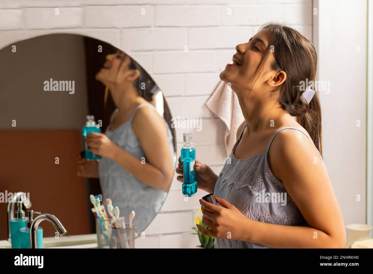 Woman gargling with mouthwash in bathroom Stock Photo