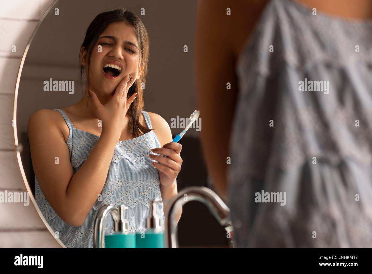 Woman suffering from toothache while brushing Stock Photo
