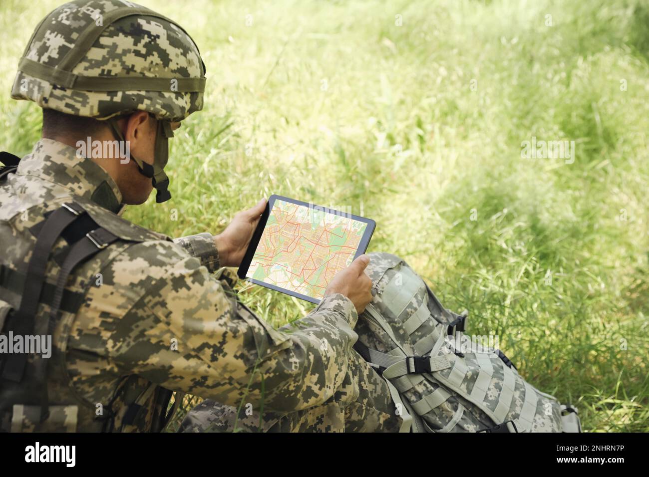 Soldier with backpack using tablet in forest Stock Photo