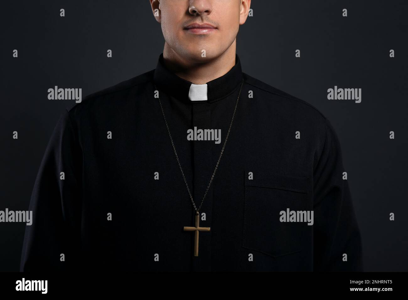 Priest with cross on black background, closeup Stock Photo