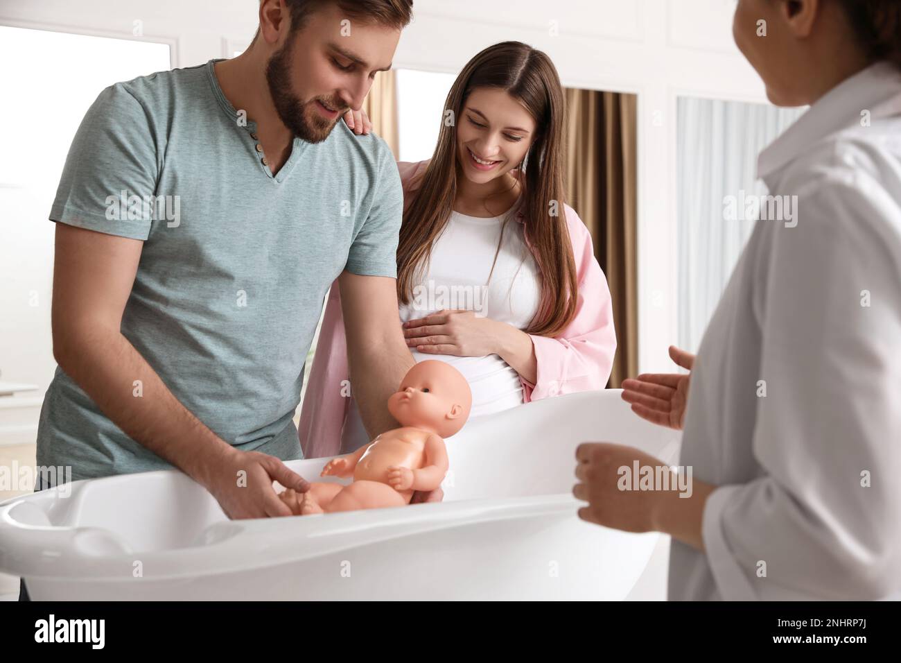 Man with pregnant wife learning how to bathe baby at courses for