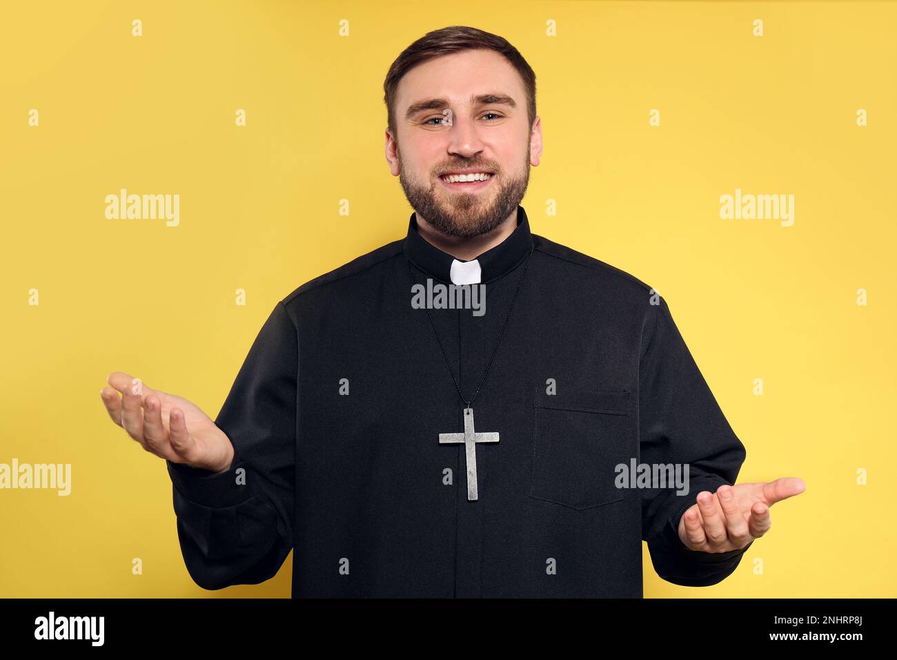 Priest wearing cassock with clerical collar on yellow background Stock Photo