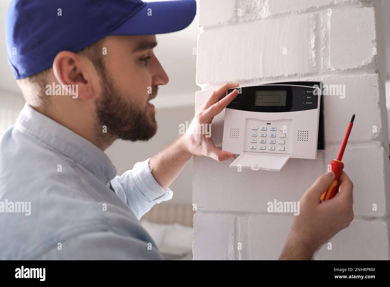 Man installing home security system on white wall in room Stock Photo