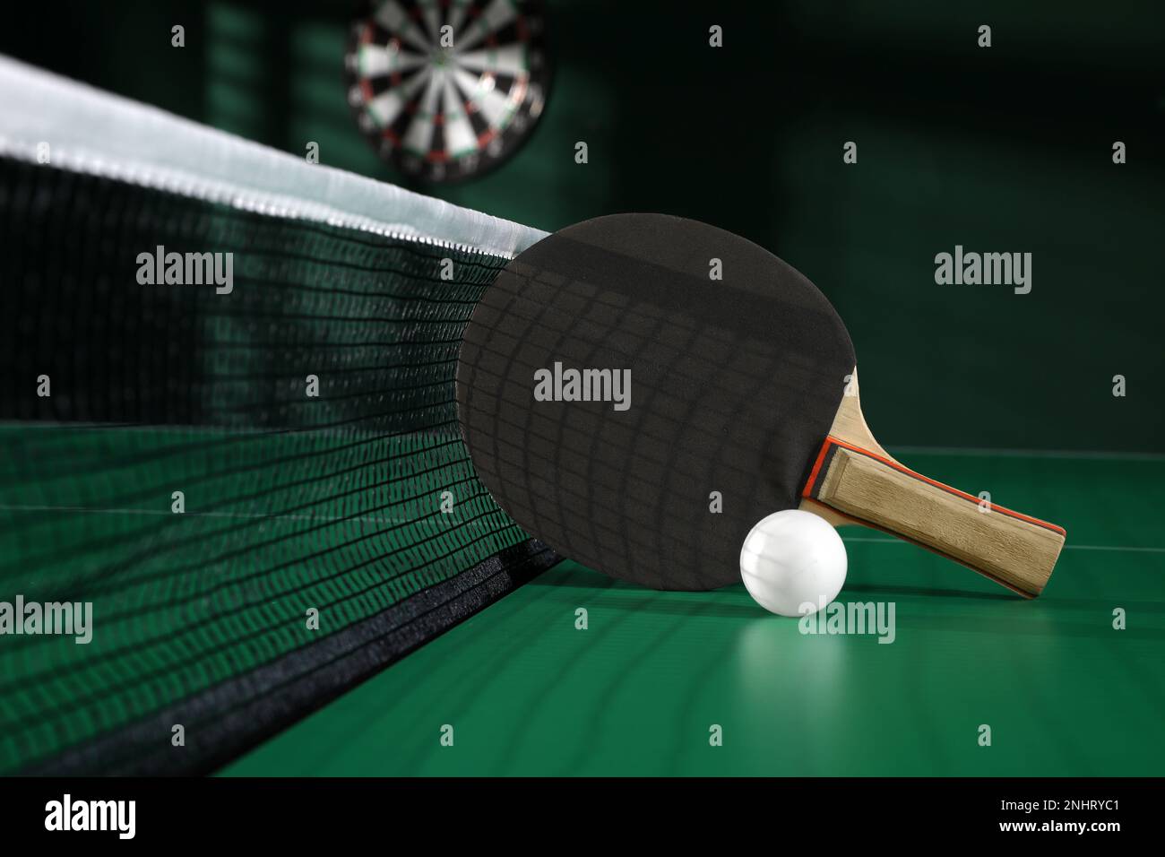 Black racket and ball on green ping pong table indoors Stock Photo - Alamy