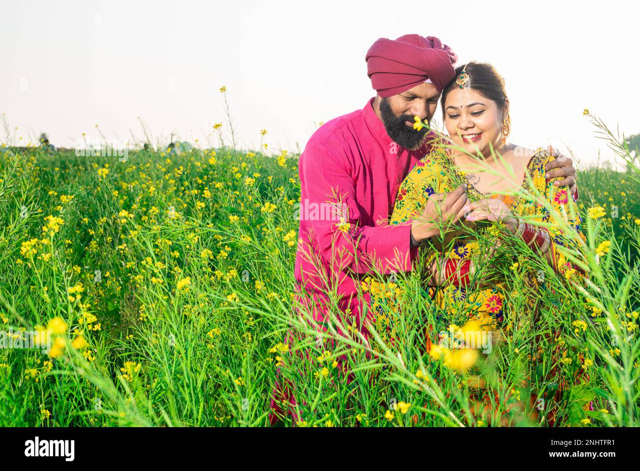 Happy young Punjabi sikh farmer couple standing together at agriculture ...