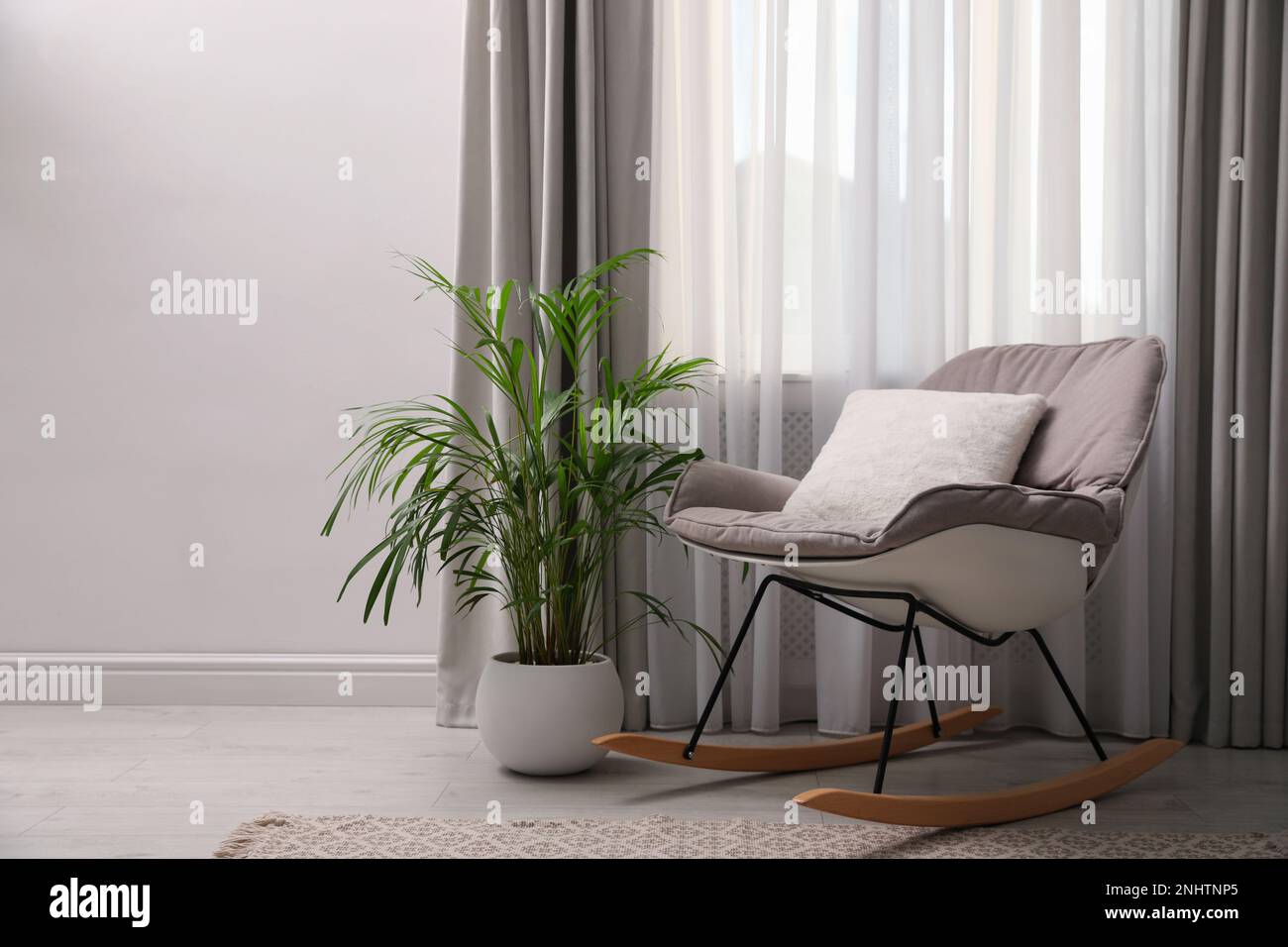 Comfortable rocking chair and beautiful plant near window indoors Stock ...