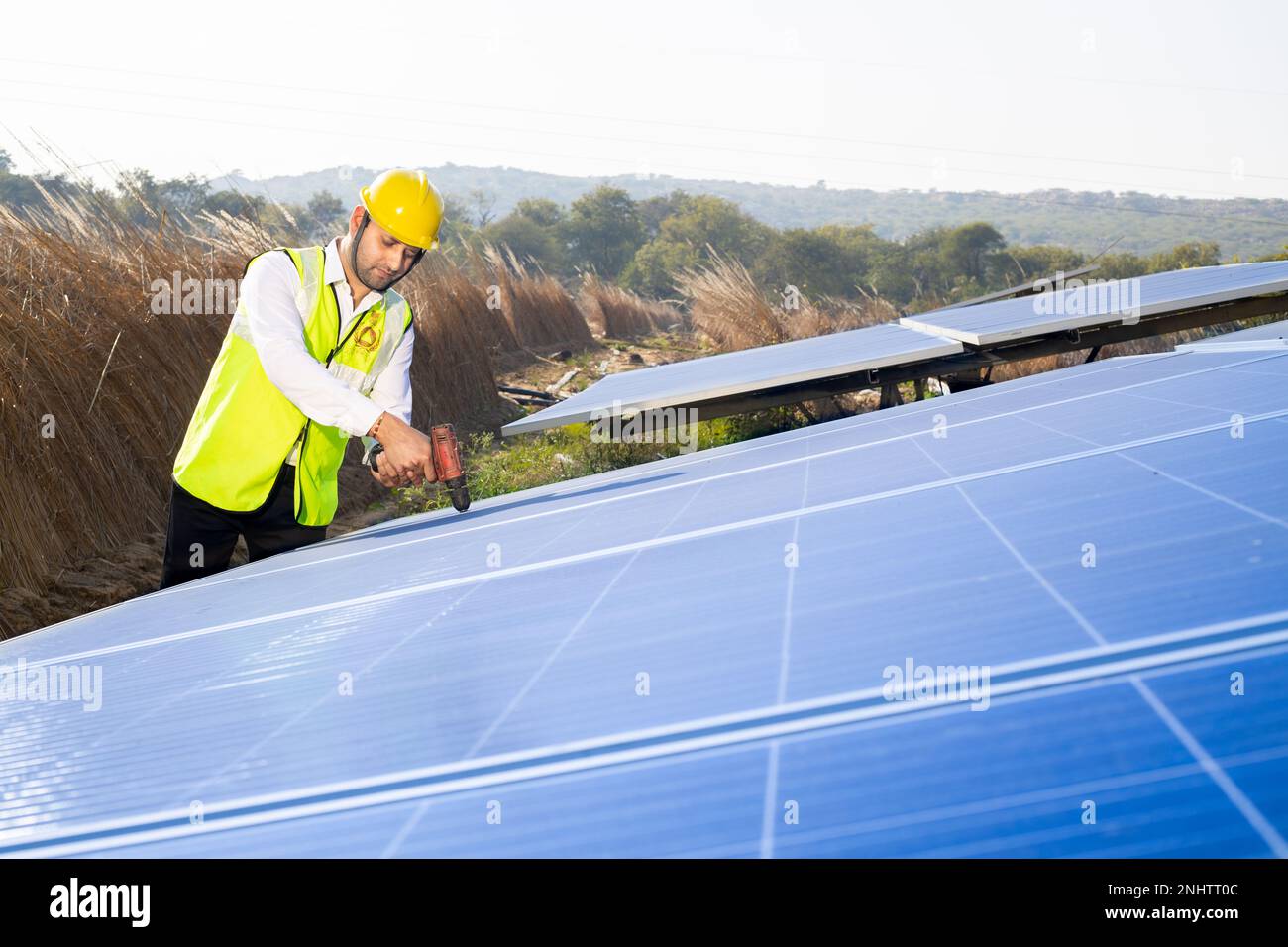 Young indian worker technician installing heavy solar panels outdoors. Exterior solar system