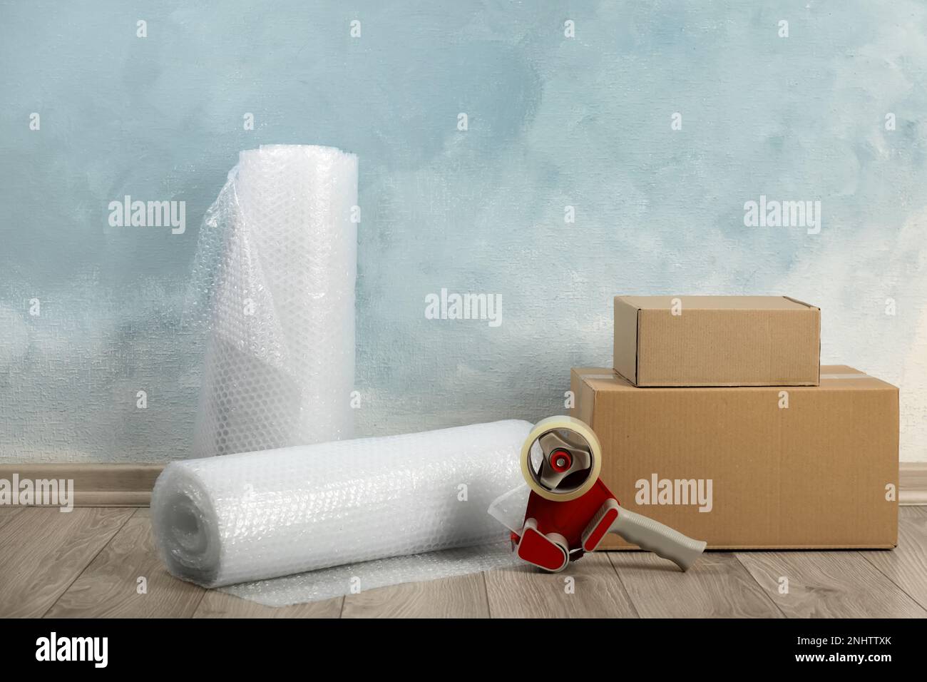 Bubble wrap rolls, tape dispenser and cardboard boxes on floor near
