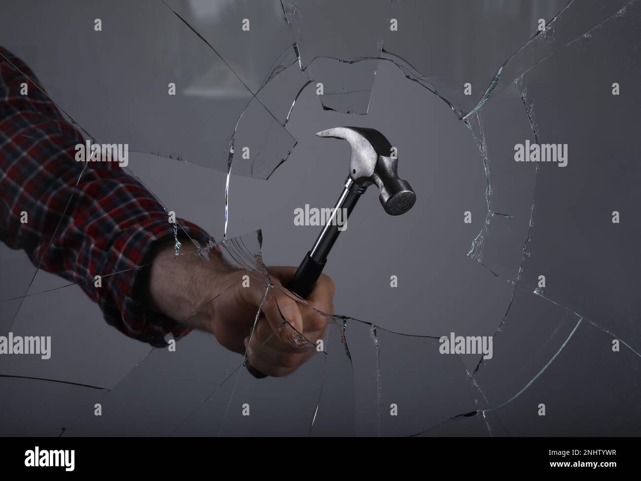 Man breaking window with hammer on grey background, closeup Stock Photo