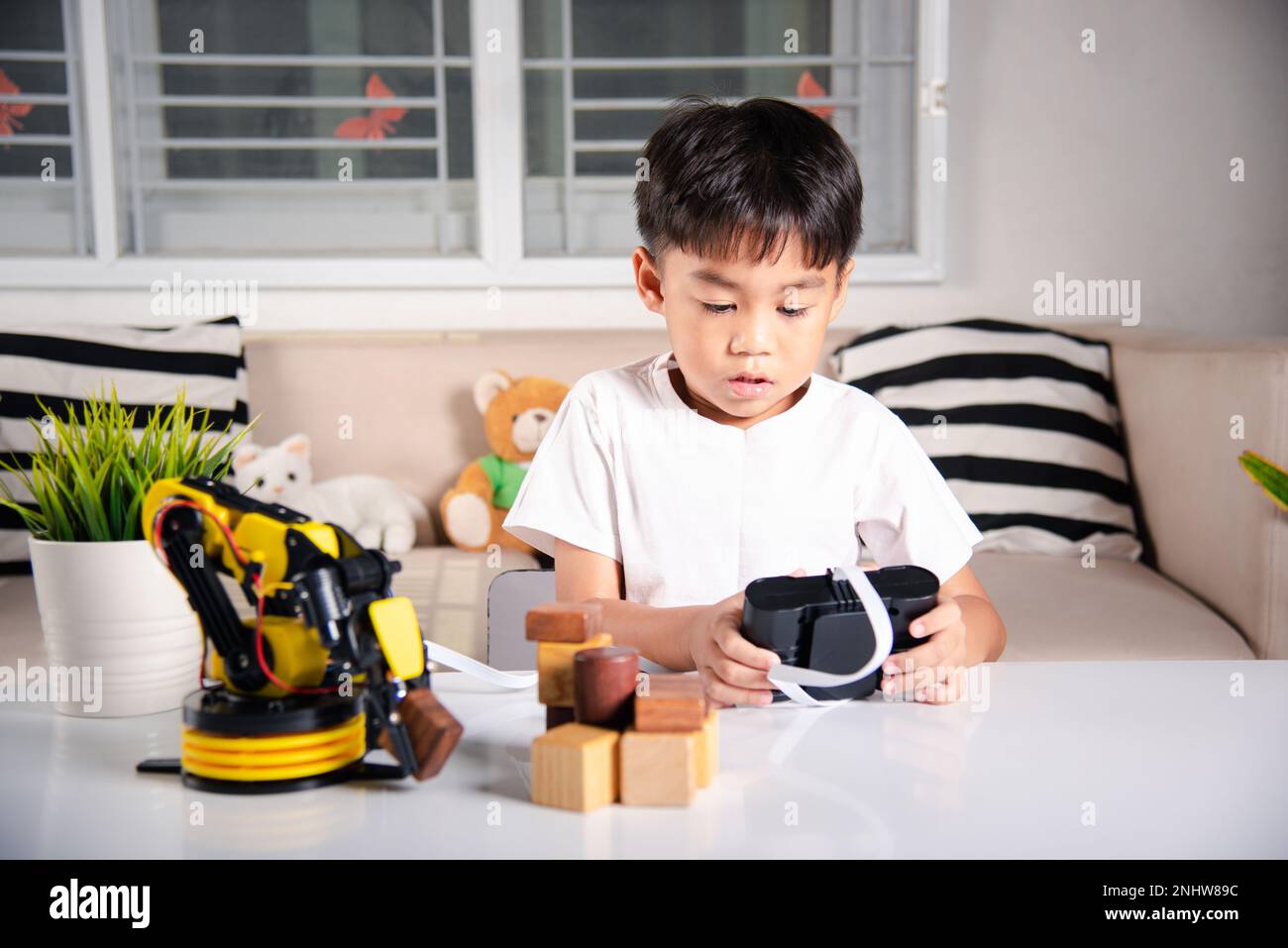 Happy Asian little kid boy using remote control playing robotic machine