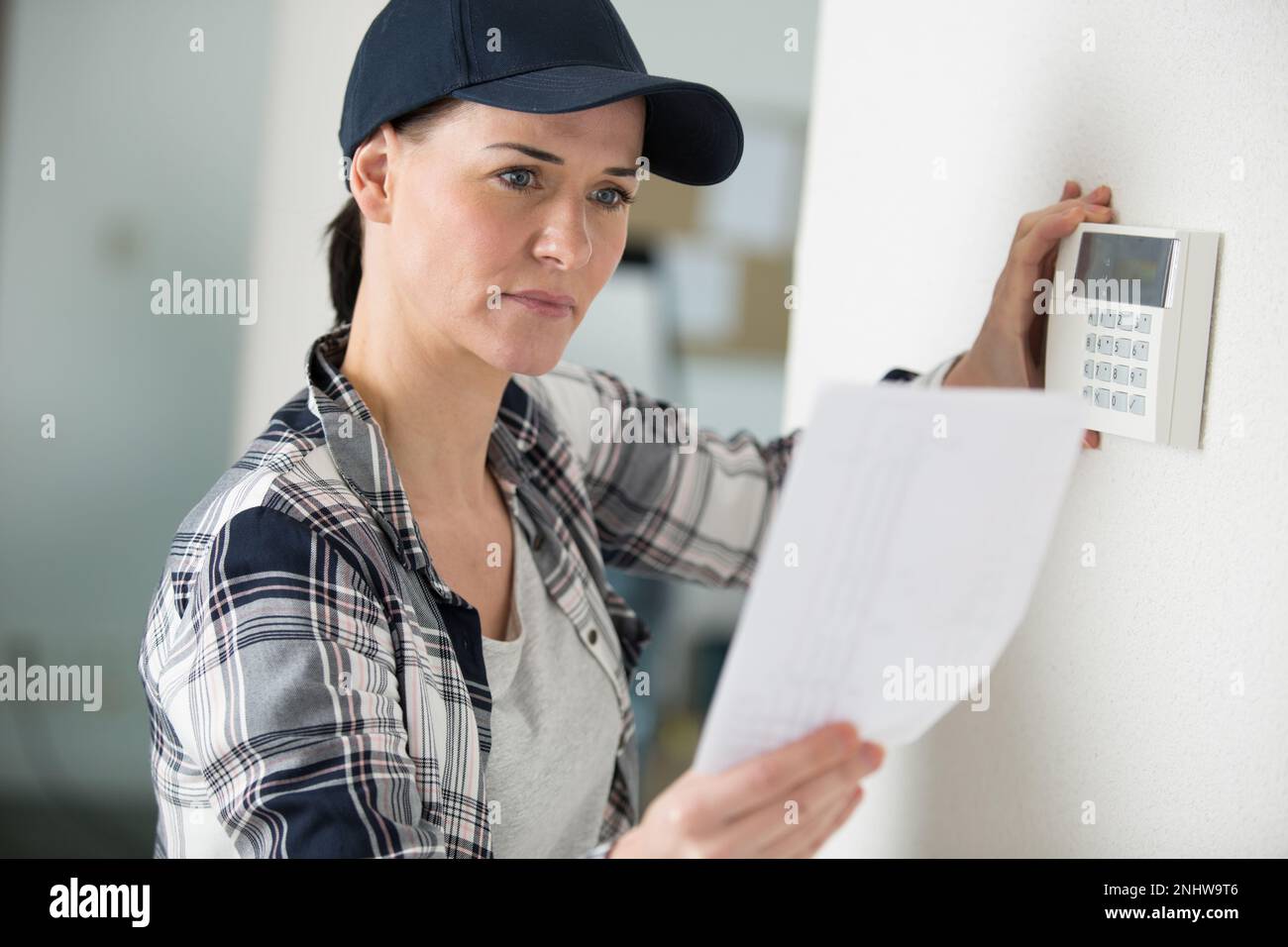 an electrician woman installing thermostat Stock Photo
