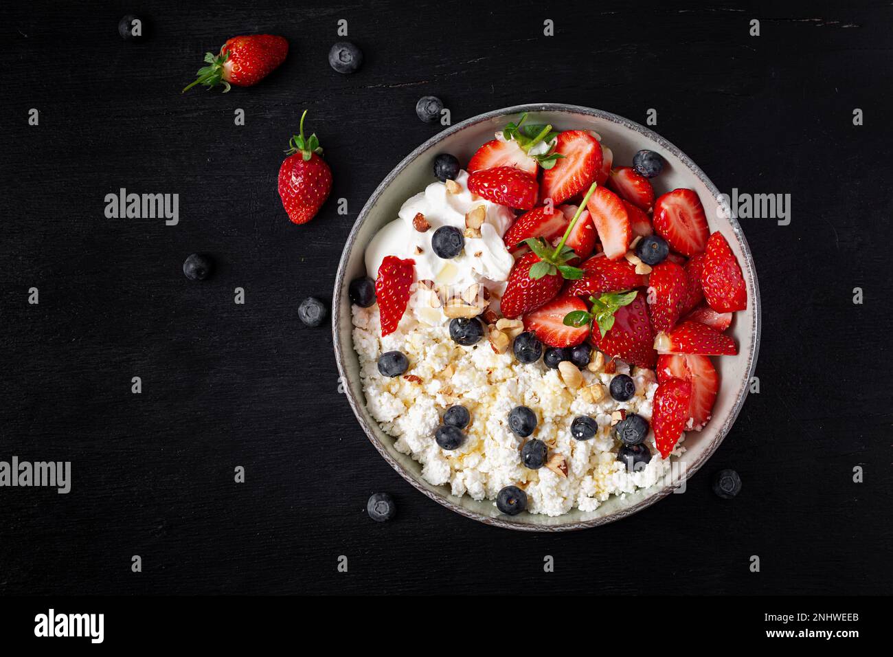 Cottage cheese, curd cheese with fresh strawberries, blueberries, nuts
