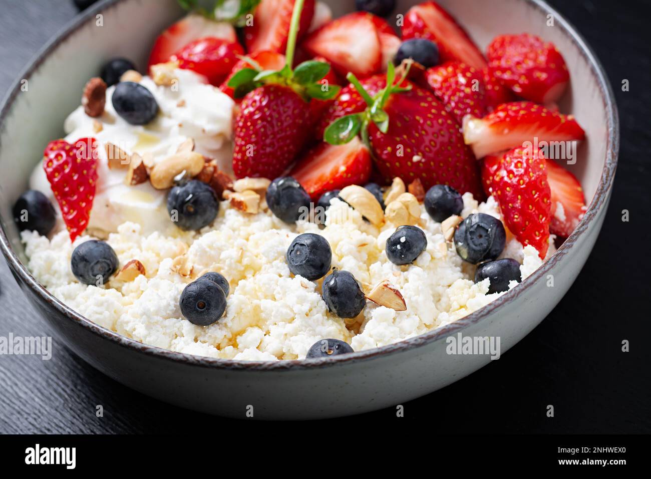 Cottage cheese, curd cheese with fresh strawberries, blueberries, nuts
