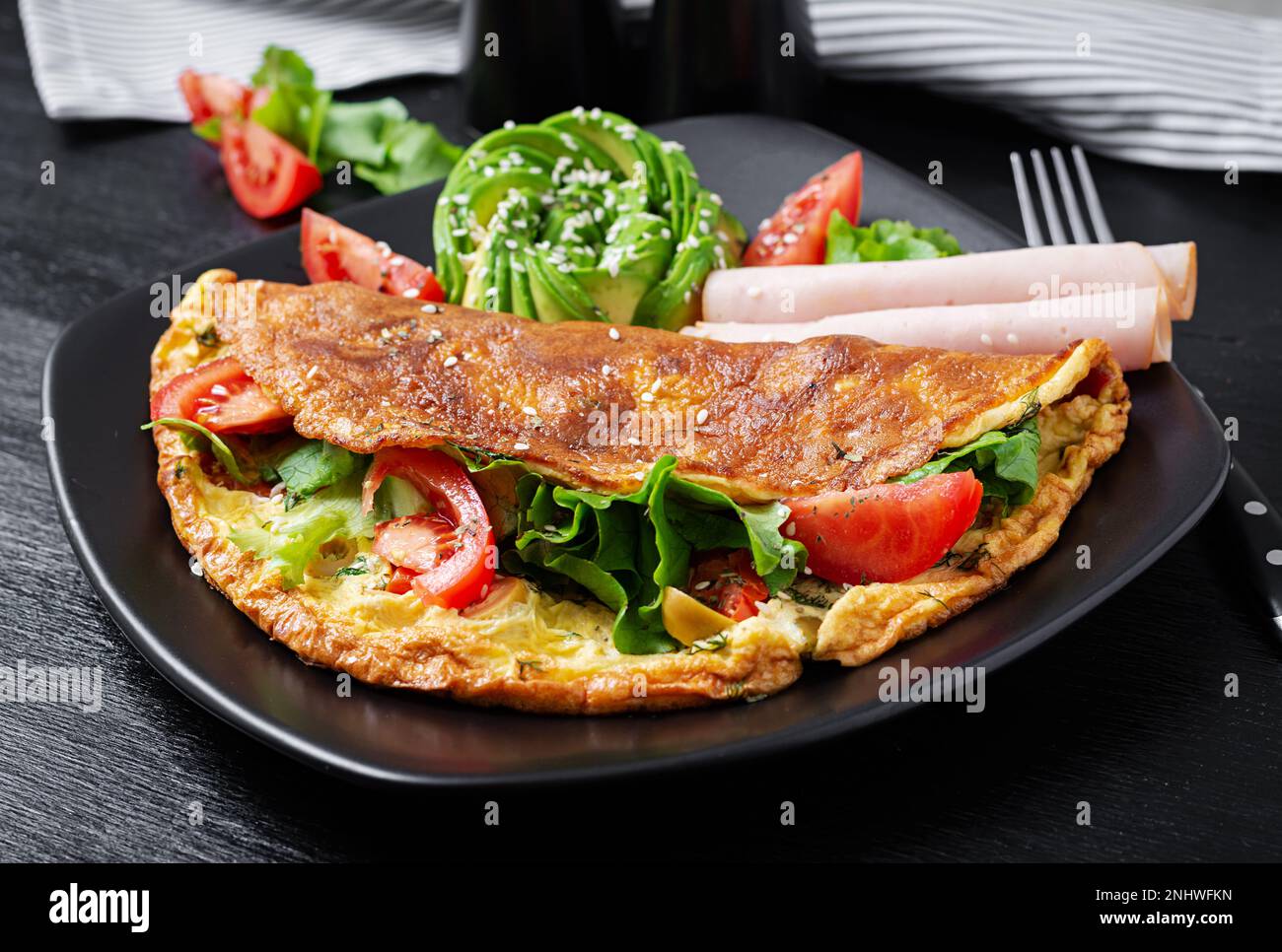 Keto breakfast. Omelette tomato, olives and avocado, ham. Ketogenic