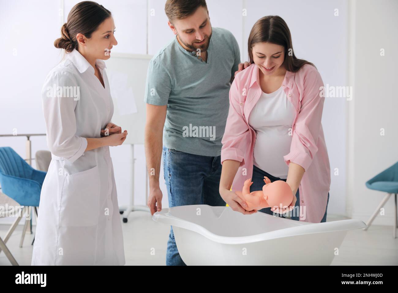Man with pregnant wife learning how to bathe baby at courses for