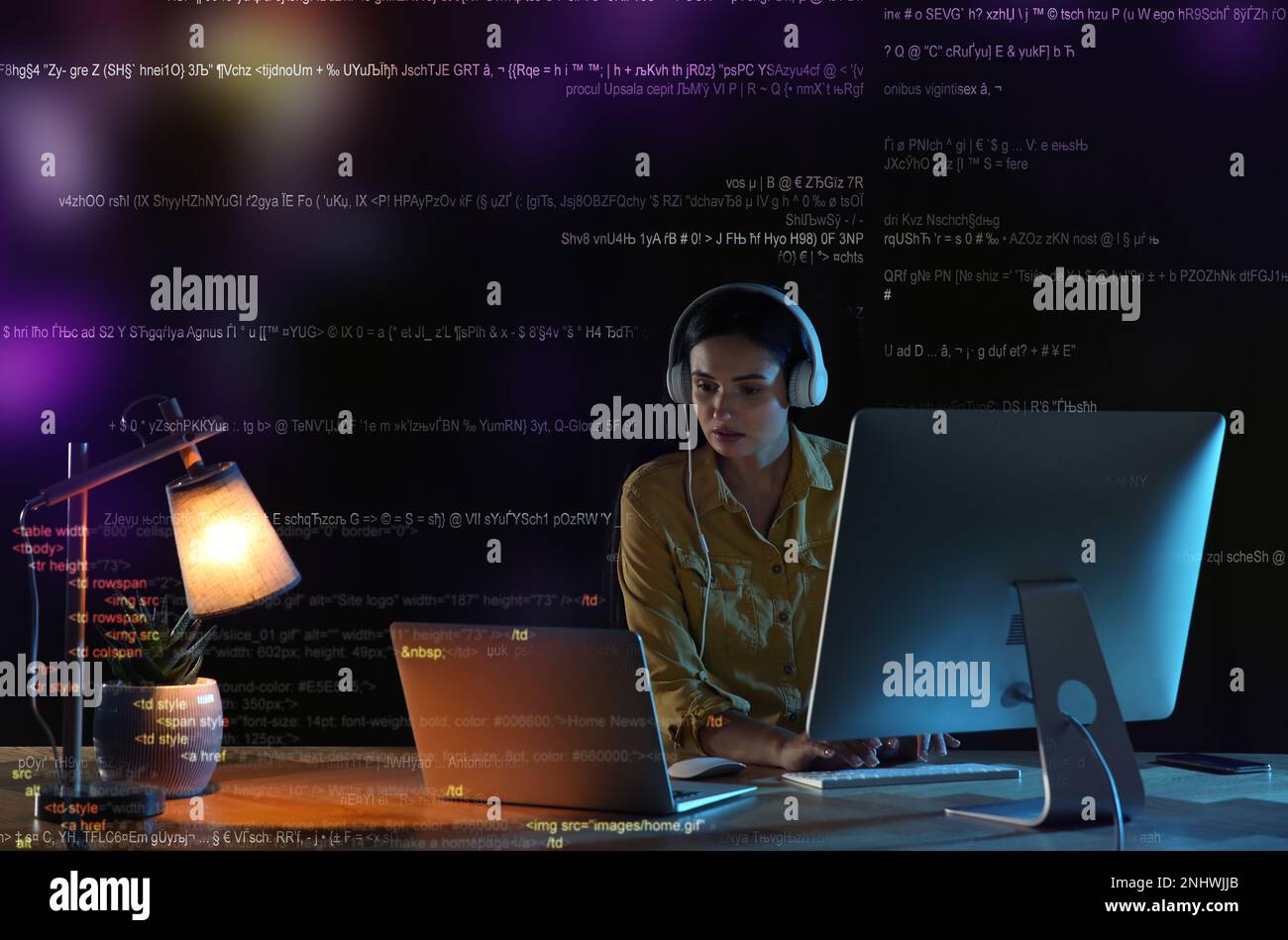 Programmer with headphones working in office at night Stock Photo