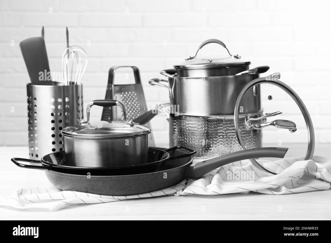 Set of clean kitchenware on white table against brick wall Stock Photo