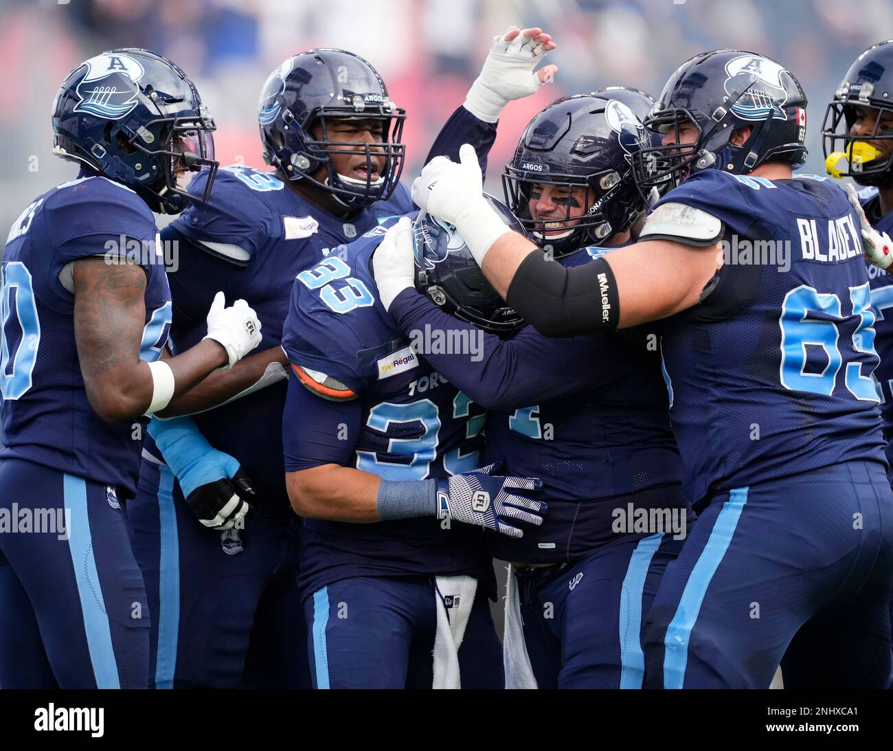 Toronto Argonauts running back Andrew Harris (33) is mobbed by teammates  after scoring a touchdown against the Montreal Alouettes during the first  half of a CFL Eastern Final football game in Toronto