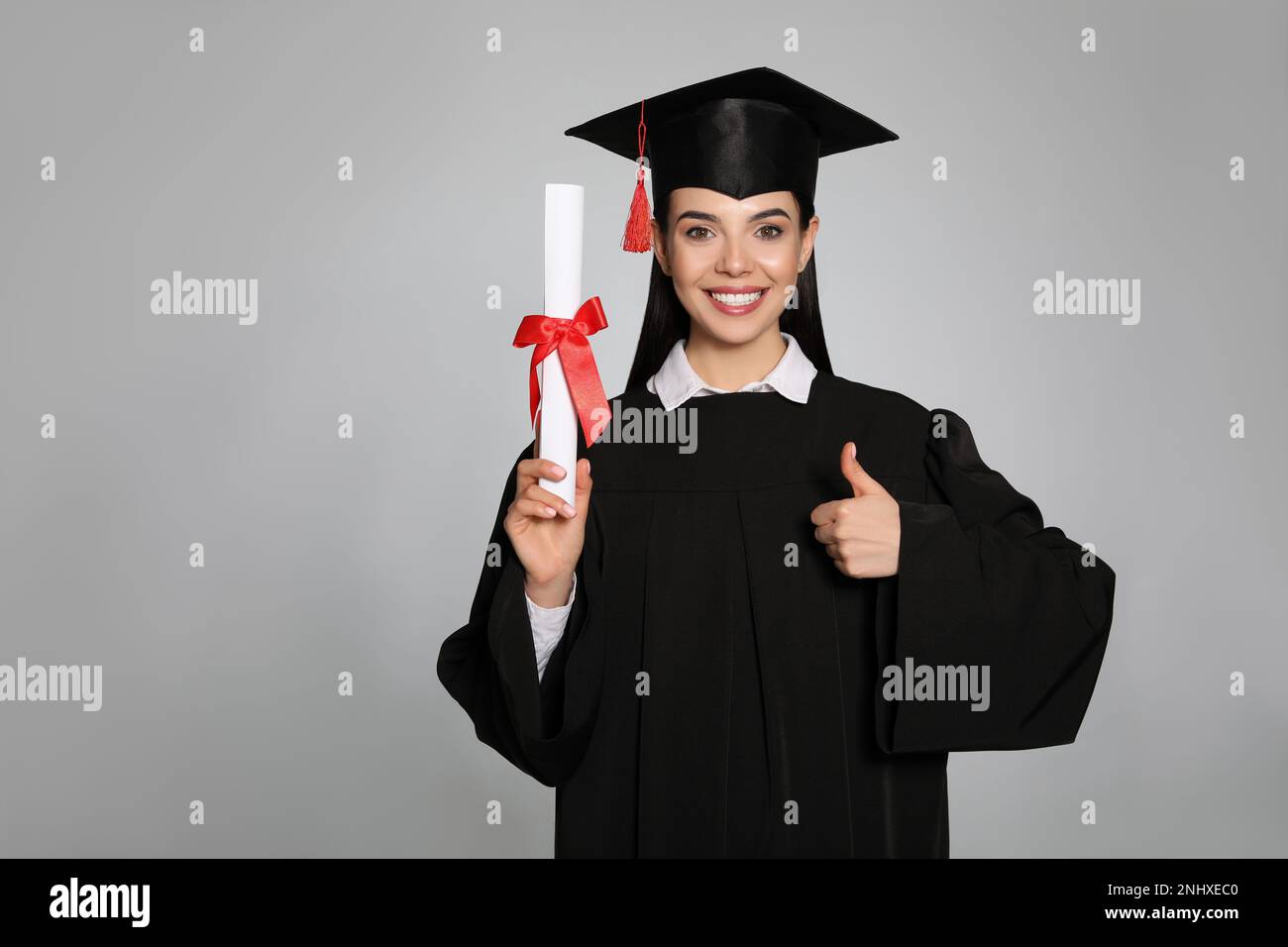 Happy student with graduation hat and diploma on grey background. Space ...
