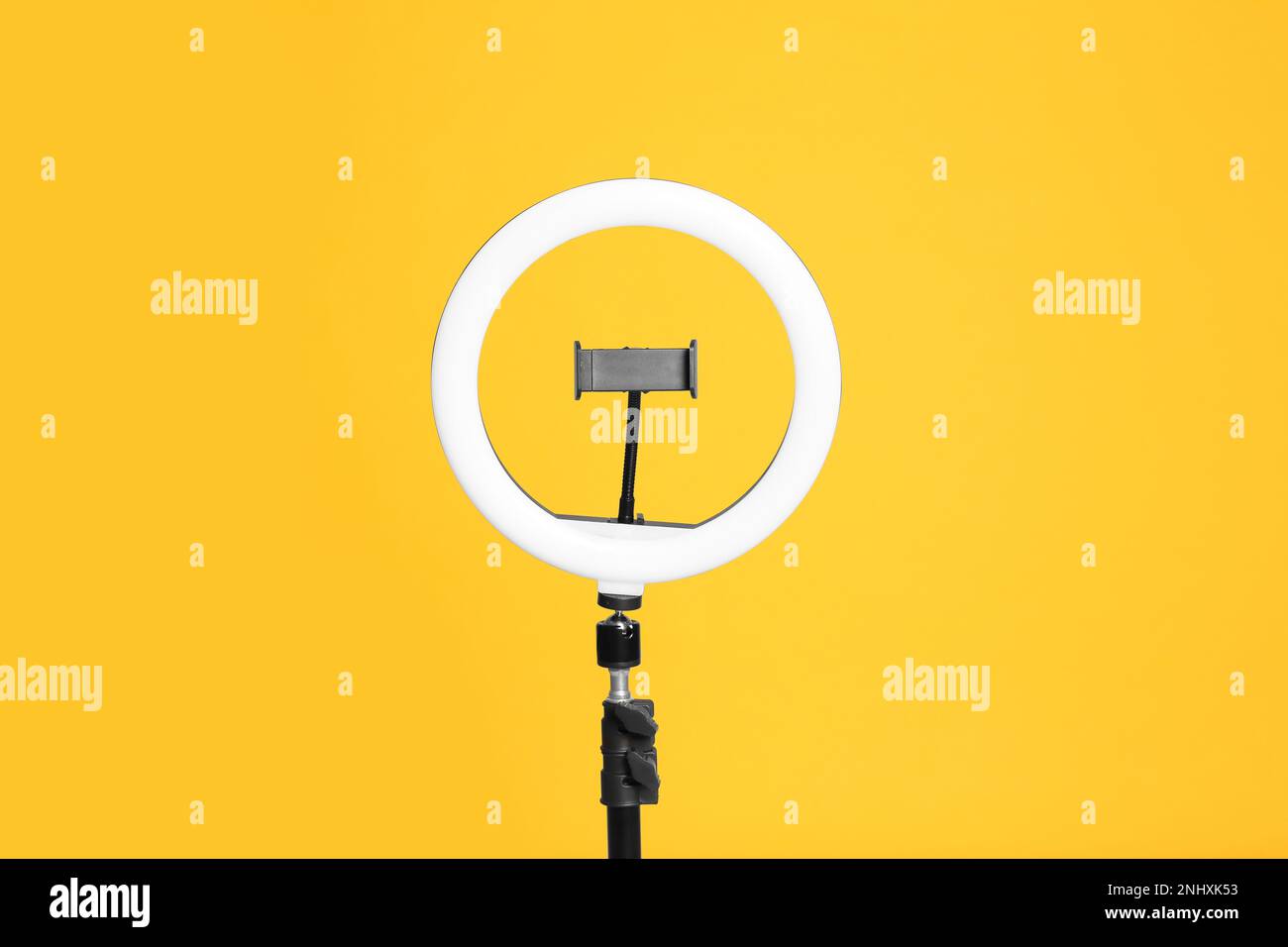 Modern tripod with ring light on yellow background Stock Photo - Alamy