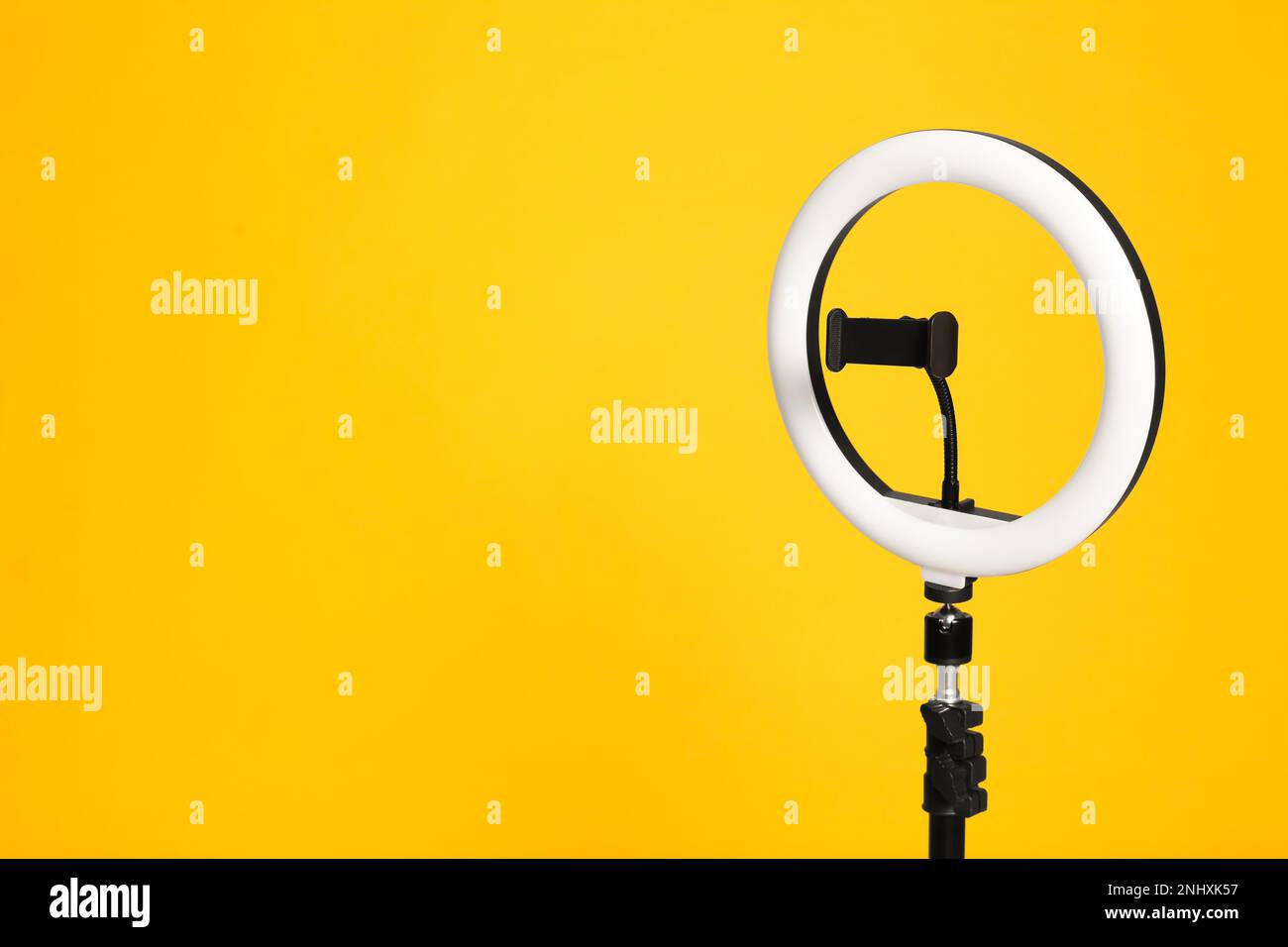 Modern tripod with ring light on yellow background. Space for text ...