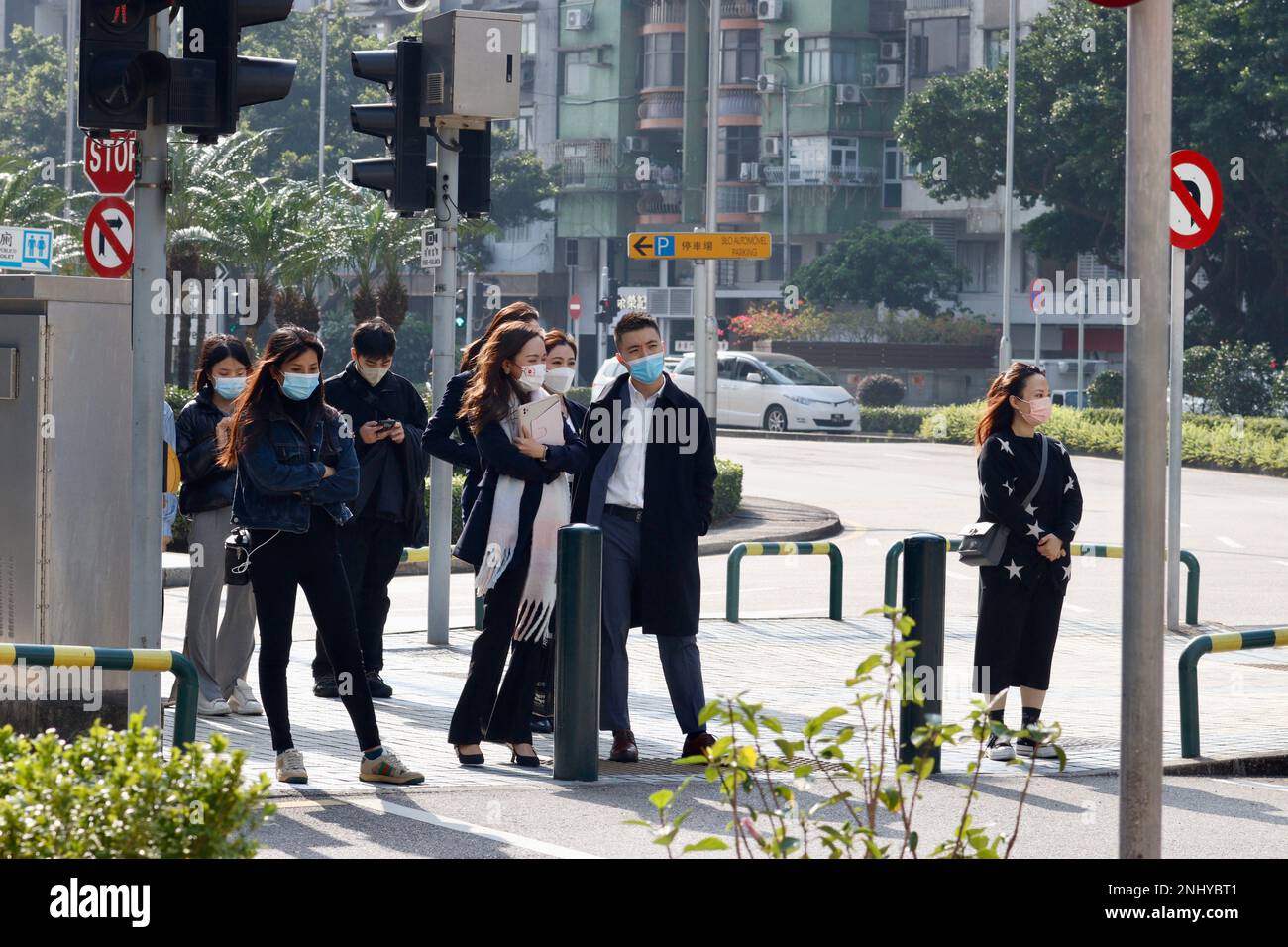 Women and men standing on a street corner in Macau, waiting for the light to change Stock Photo