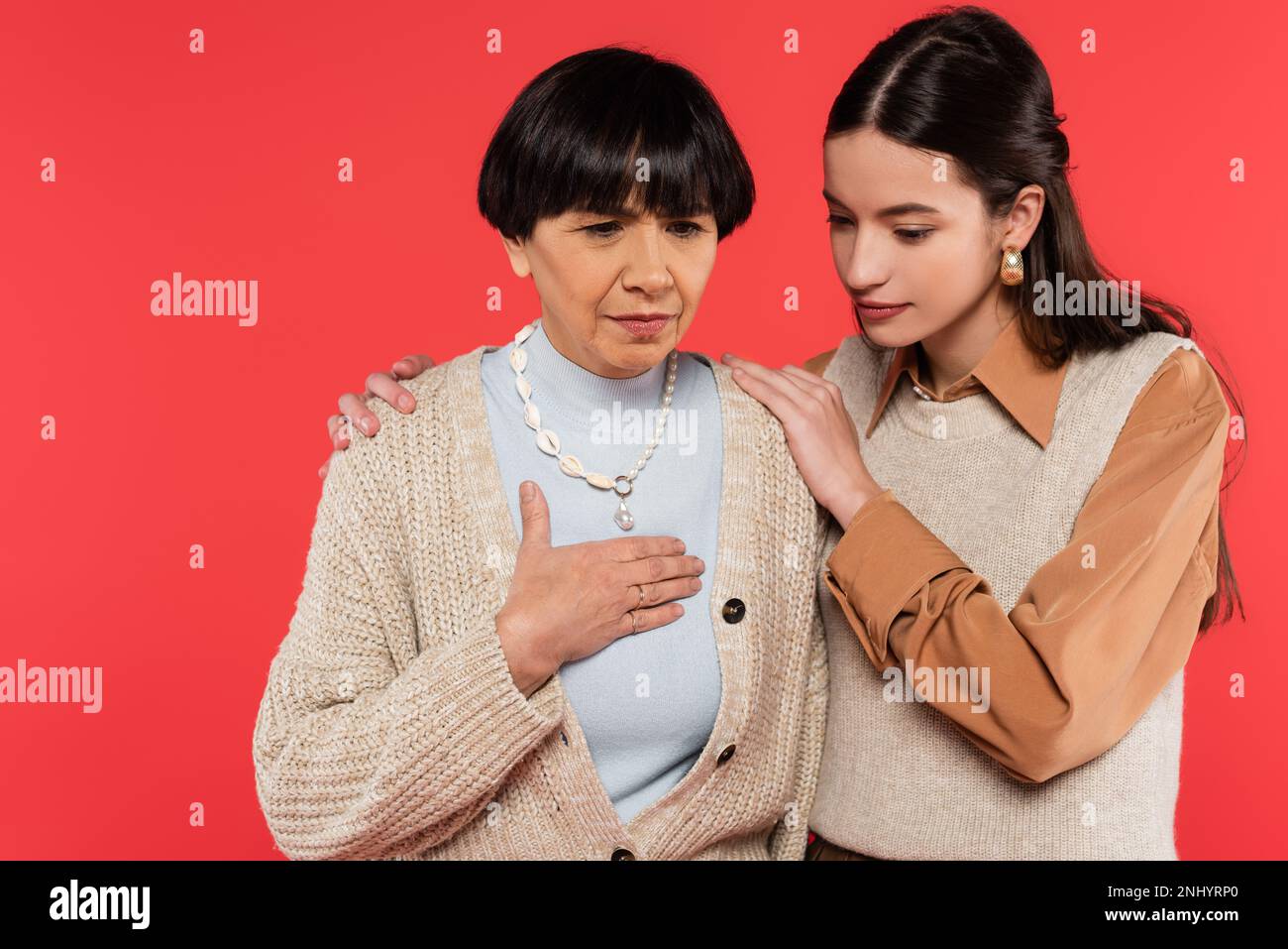worried asian woman hugging middle aged mother touching chest while