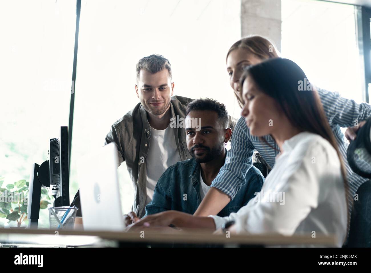 Friendly creative diverse colleagues team discuss online project use computer at workplace Stock Photo