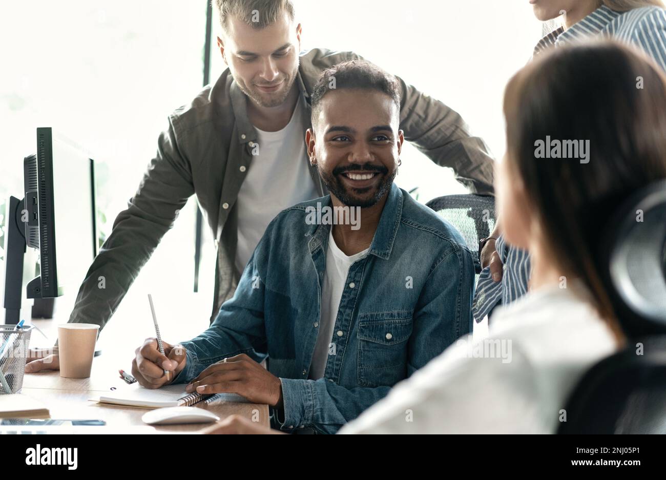 Friendly creative diverse colleagues team discuss online project use computer at workplace Stock Photo