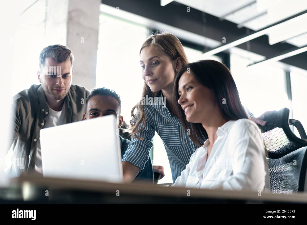 Friendly creative diverse colleagues team discuss online project use computer at workplace Stock Photo