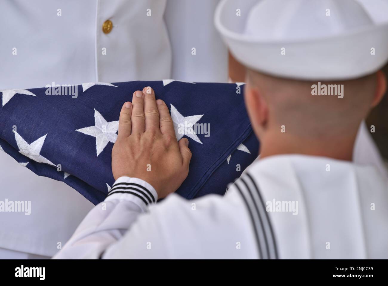 A sailor assigned to U.S. Navy Region Hawaii hands off a U.S. flag during an internment ceremony for U.S. Navy Water Tender 1st Class Milo E. Phillips at the National Memorial Cemetery of the Pacific, Honolulu, Hawaii, August 4, 2022. Phillips was assigned to the USS Oklahoma, which capsized after sustaining multiple hits from Japanese aircraft and torpedoes, causing the deaths of more than 400 crew members on Dec. 7, 1941, at Ford Island, Pearl Harbor. Stewart was recently identified through DNA analysis by the Defense POW/MIA Accounting Agency (DPAA) forensic laboratory and laid to rest with Stock Photo