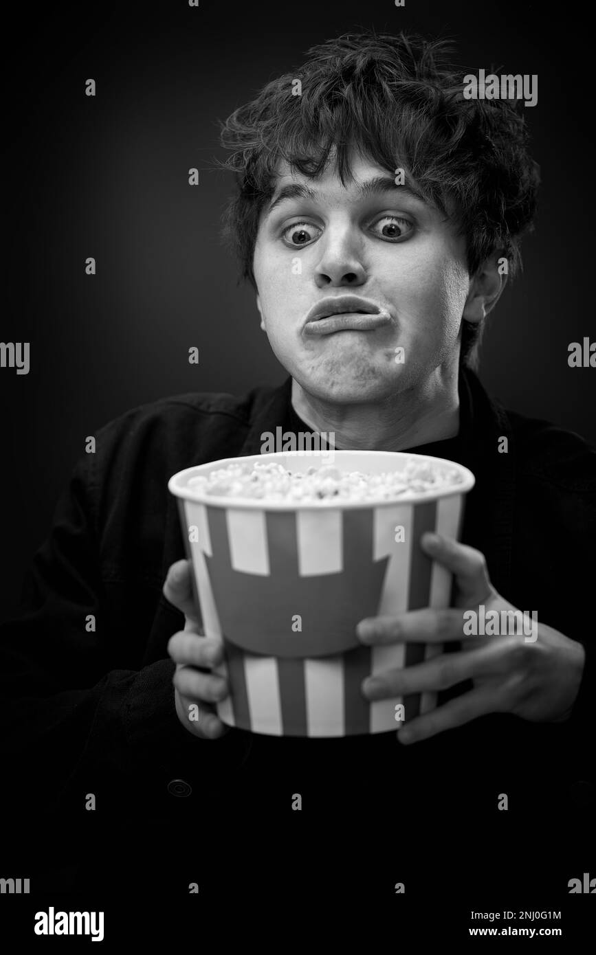 portrait of crazy young man holding bucket of popcorn Stock Photo