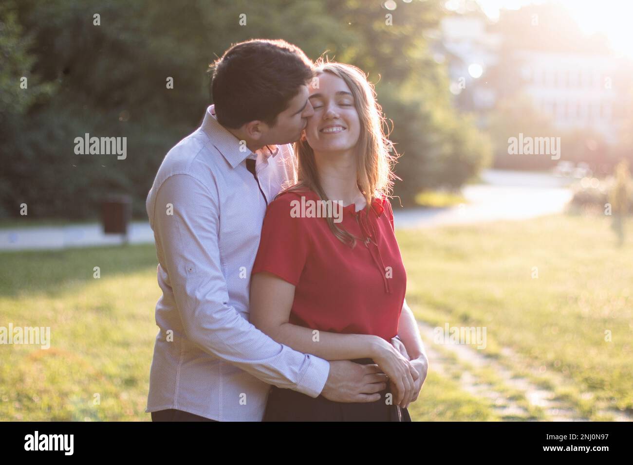 Young couple in love spending time together in the park, the man kisses ...