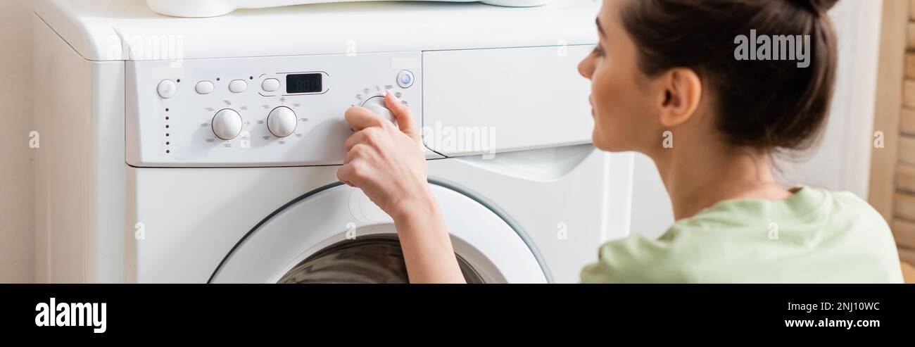 Side view of young woman switching washing machine at home, banner,stock image Stock Photo