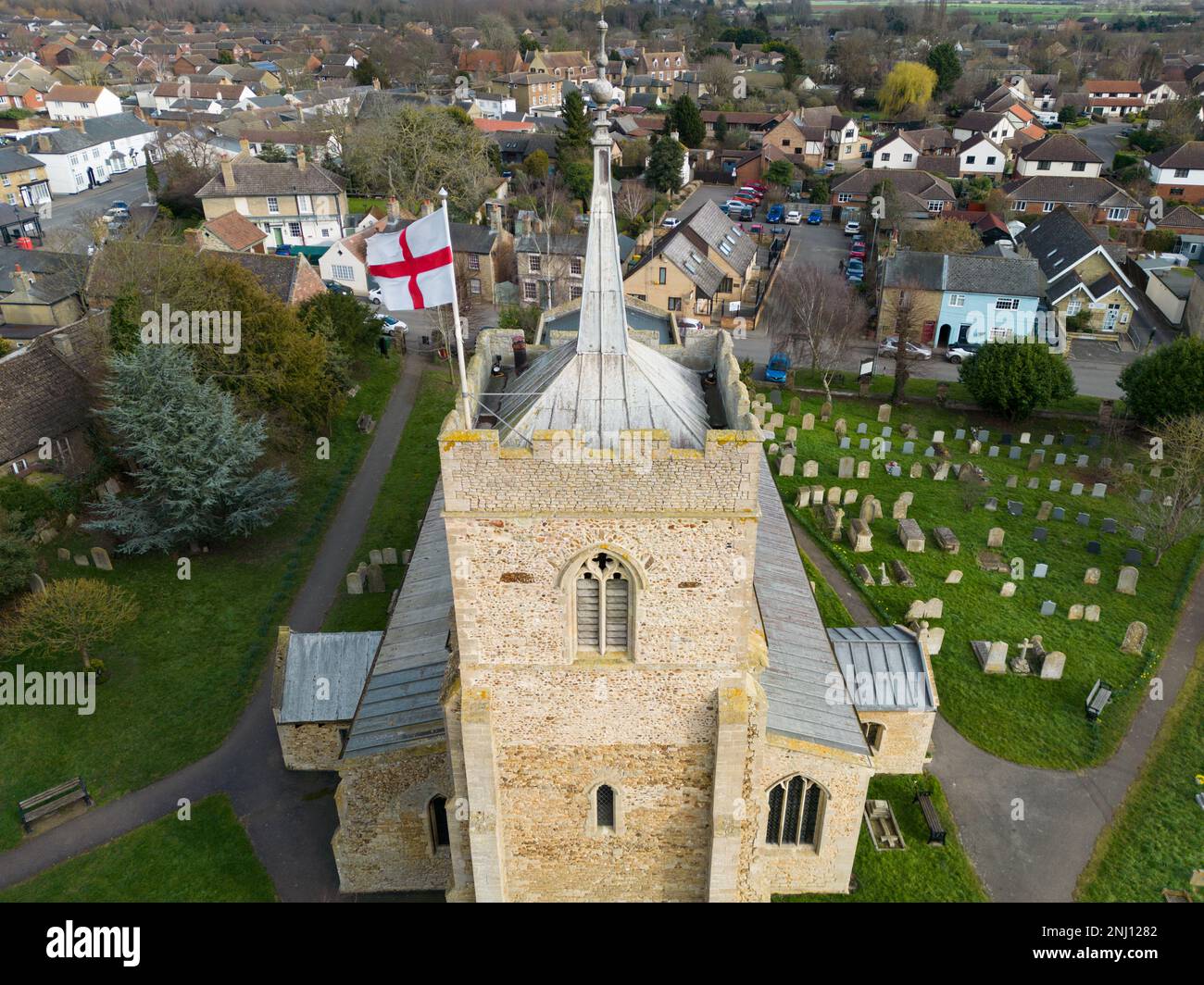 Aerial view of a St Georges English nation flag seen atop on English village church tower. The fine leaded roof on the tower is seen. Stock Photo