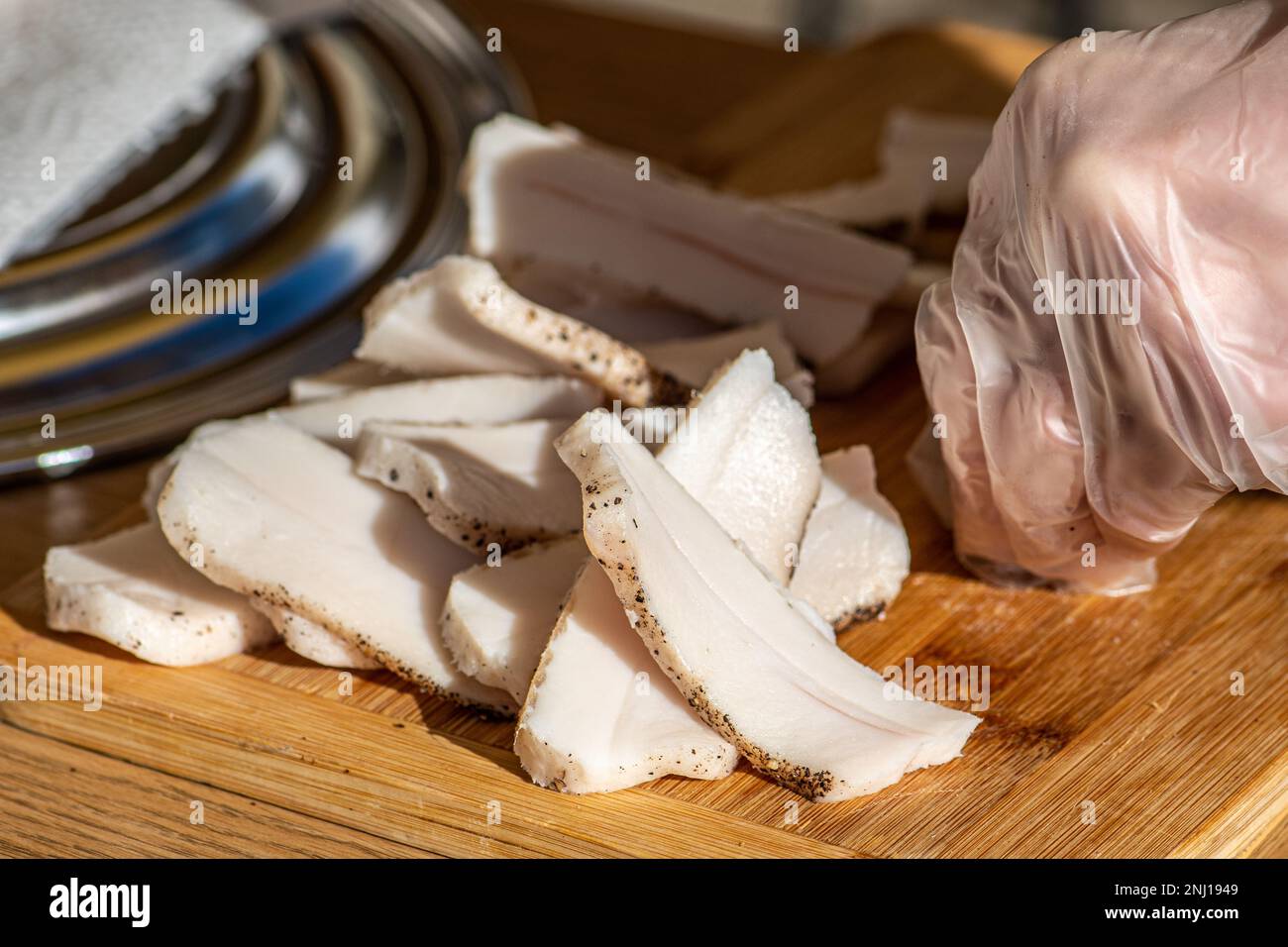 Pieces of lard or bacon, sliced thinly for consumption, on a wooden cutting board in a street food market, close up Stock Photo