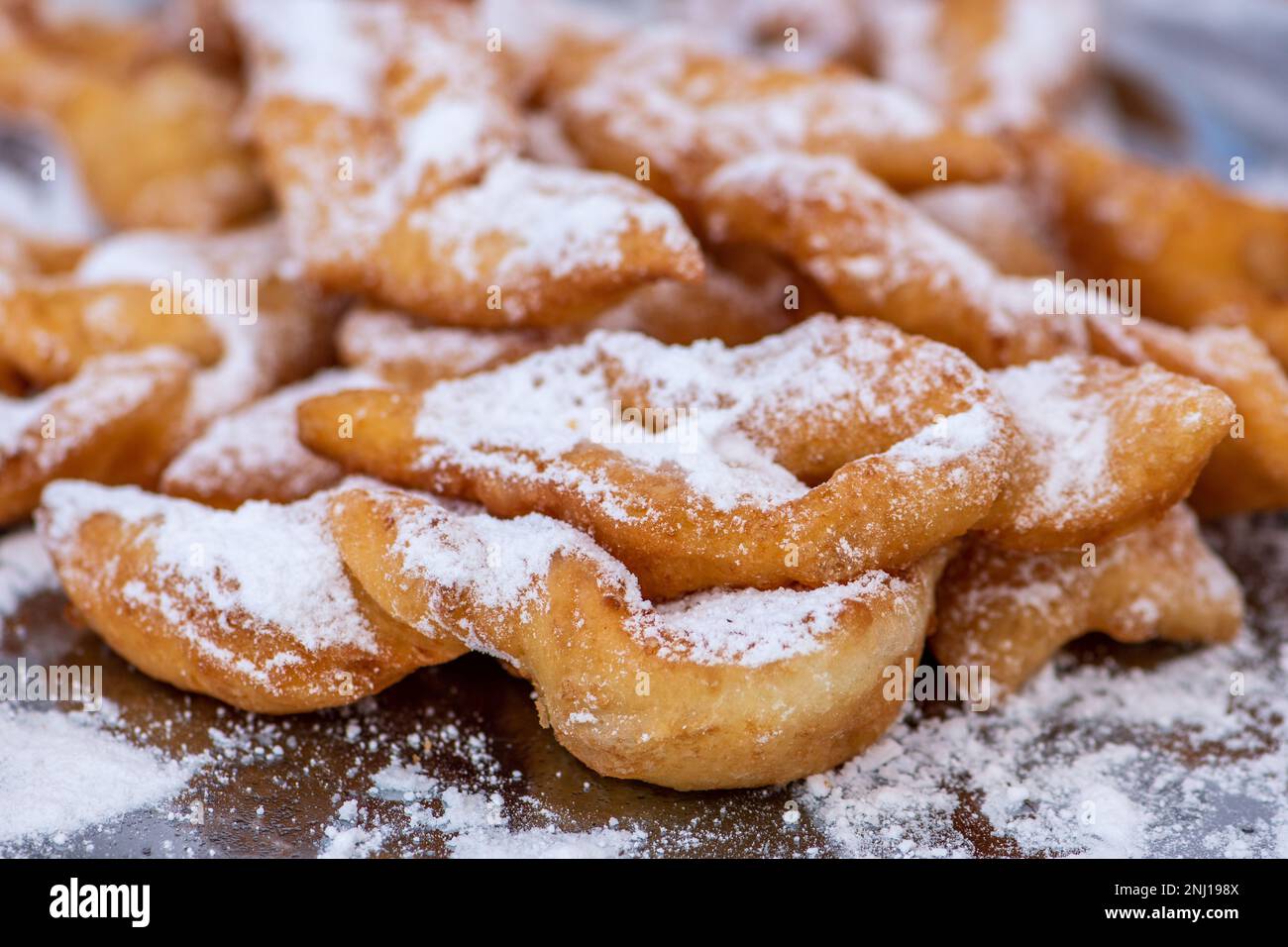 Fried pastrie of Carnival, strips of fried dough typically made on Mardi Gras covered by powdered sugar, close up Stock Photo