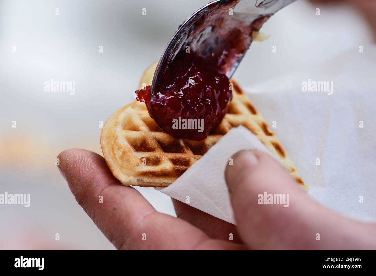 Preparing waffle or waffles with jam, dish made from leavened butter or dough that is cooked between two plates that are patterned to give a character Stock Photo