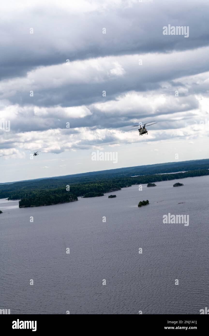 A U.S. Army CH-47 Chinook helicopter and a UH-60 Black Hawk helicopter assigned to the 1st Squadron, 214th General Support Aviation Battalion, 12th Combat Aviation Brigade, conduct low level flight training at Tampere, Finland, Aug. 4, 2022. 12th Combat Aviation Brigade is one of the units to support U.S. European Command theater strategy by demonstrating U.S. commitment to European Allies and Partners and highlighting U.S. capabilities to diverse audiences. 12 CAB is among other units assigned to V Corps, America's Forward Deployed Corps in Europe. They work alongside NATO Allies and regional Stock Photo