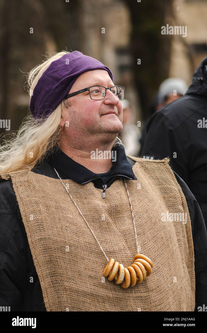 Man in a Lithuanian folk festival with sushki, traditional Ukrainian and Lithuanian, Eastern European small, crunchy, mildly sweet bread, vertical Stock Photo