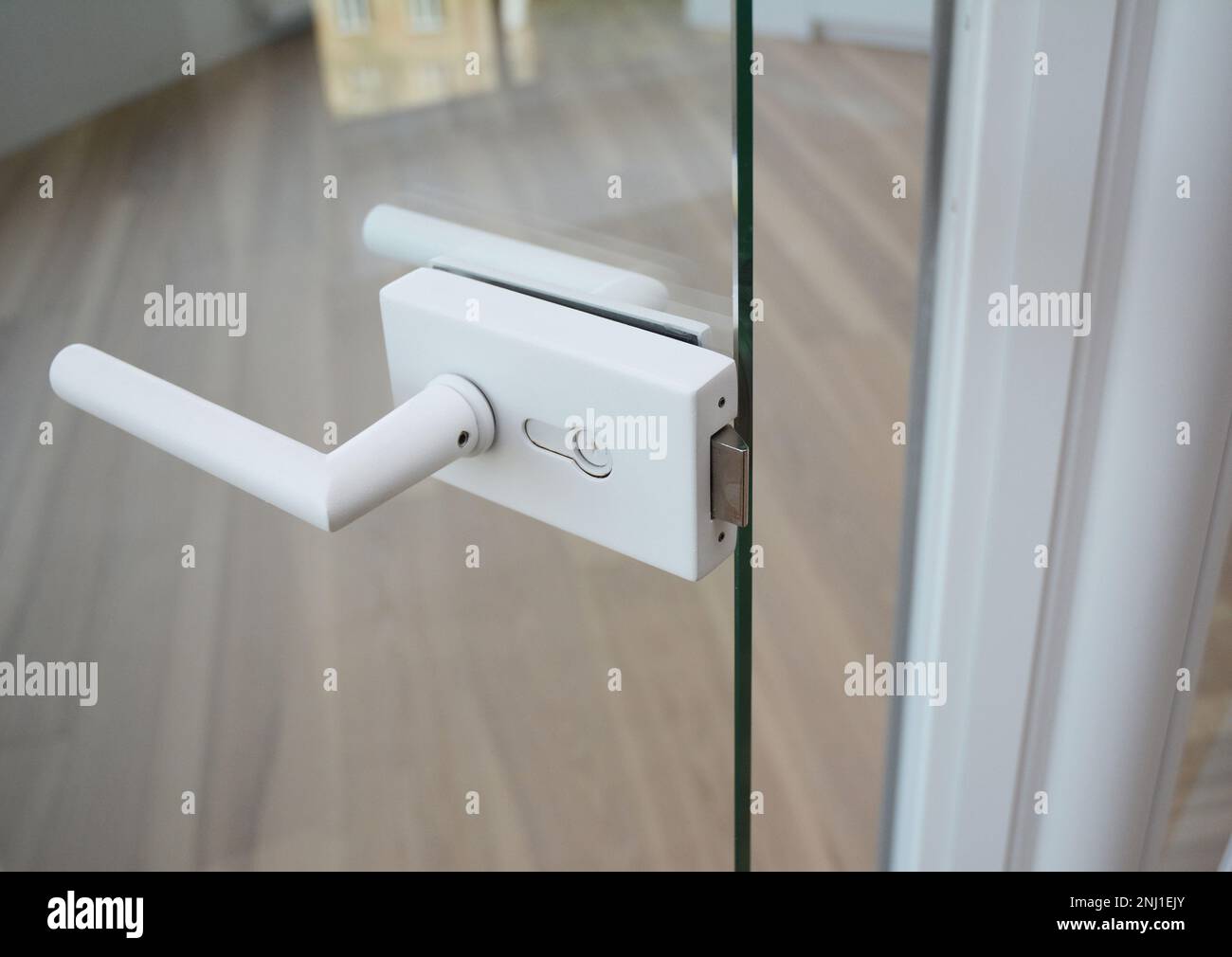 Glass Door handle. Glass door knob with handle in open glass door modern room with wooden floor. Stock Photo