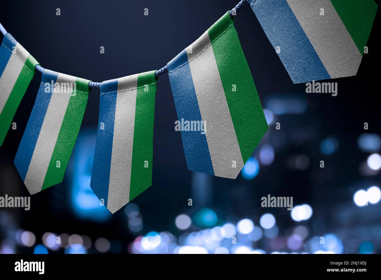 A garland of Sierra Leone national flags on an abstract blurred ...