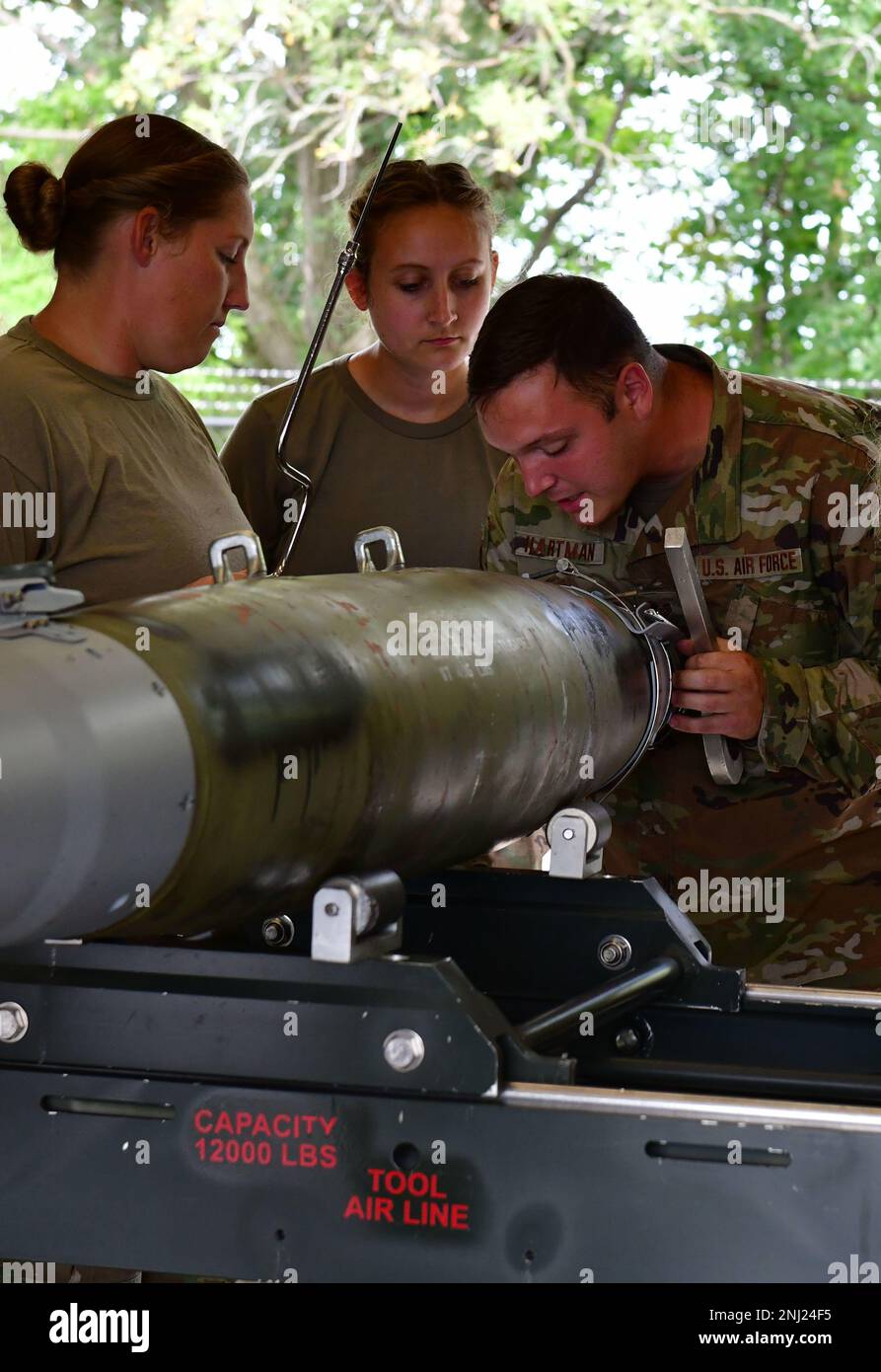 From left, U.S. Air Force Master Sgt. Chelsea R. Thompson, senior munitions controller, and Tech. Sgt. Jolee C. Edge, conventional maintenance crew chief, watch as Staff Sgt. Kaleb E. Hartman, a combat munitions training instructor, explains which items to check for when tightening the front strake straps on a GBU-54 bomb August 4, 2022, at the Fort Wayne Air National Guard base, Fort Wayne, Indiana. Members of the 122nd Fighter Wing Munitions Flight complete refresher training every 18 months. Stock Photo