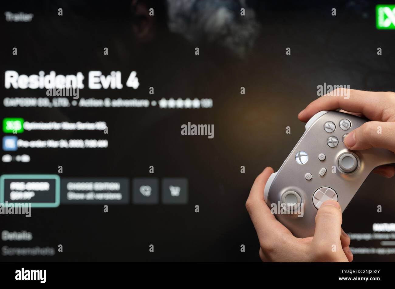 New york, USA - February 20, 2023: Buy new game Resident Evil 4 in online microsoft xbox store with gamepad controller in hand Stock Photo